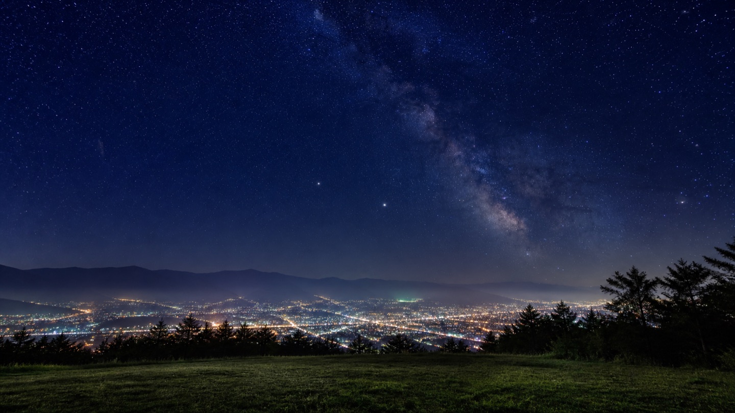 甲府盆地の夜景の上に広がる満天の星空